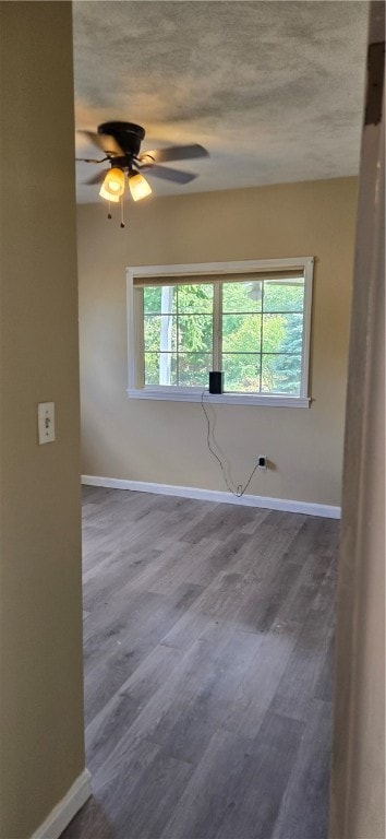 spare room featuring a healthy amount of sunlight, a textured ceiling, and hardwood / wood-style flooring