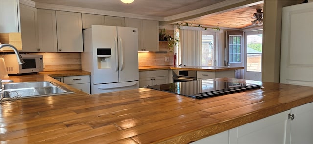 kitchen featuring white refrigerator with ice dispenser, kitchen peninsula, and butcher block counters