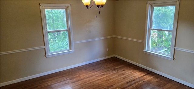 spare room featuring hardwood / wood-style flooring and a notable chandelier