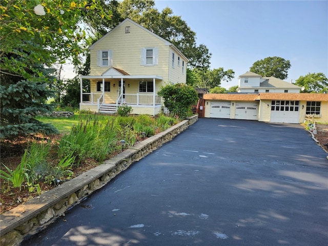 view of front of home with a porch, a garage, and an outbuilding