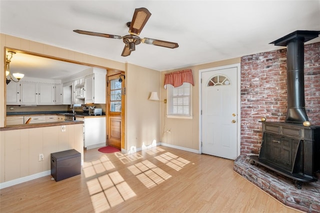 kitchen with ceiling fan, white cabinets, brick wall, and light wood-type flooring