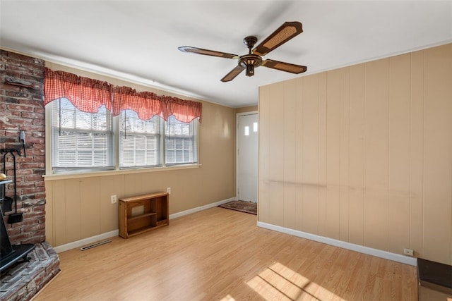 interior space with a wood stove, light hardwood / wood-style flooring, and ceiling fan