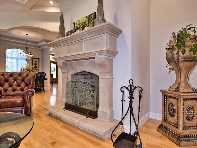 living room with a fireplace, an inviting chandelier, and light wood-type flooring