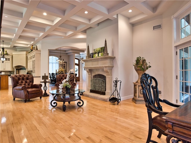 living room featuring beamed ceiling, light hardwood / wood-style floors, and a healthy amount of sunlight