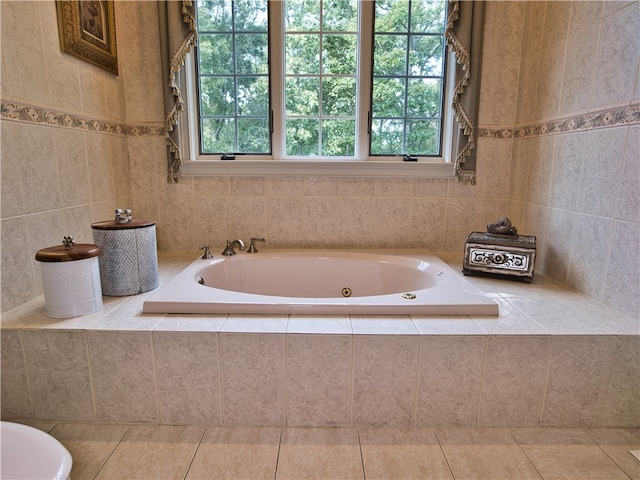 bathroom with tiled bath, plenty of natural light, and tile walls