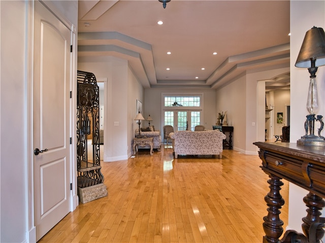 living room featuring a raised ceiling, light hardwood / wood-style flooring, and french doors