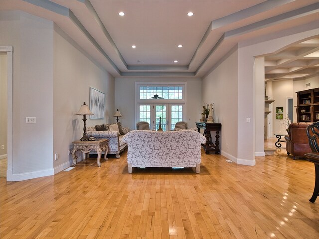 living room with french doors, light hardwood / wood-style floors, and a tray ceiling