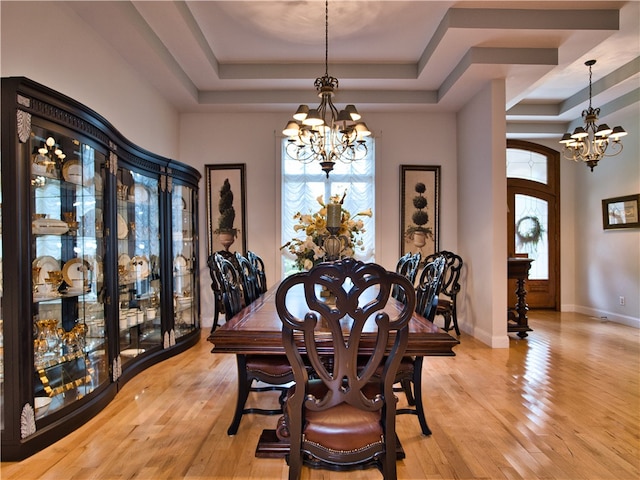 dining space featuring a chandelier, a tray ceiling, and light hardwood / wood-style flooring