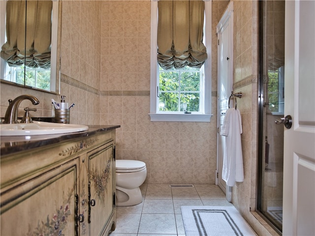 bathroom with tile patterned flooring, plenty of natural light, toilet, and tile walls