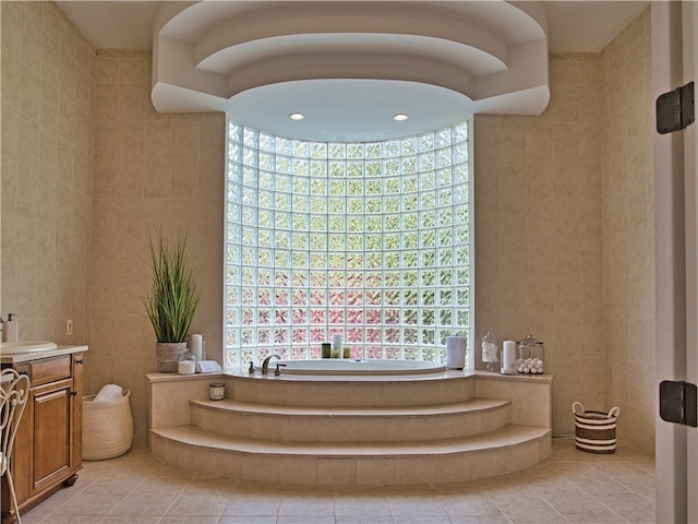 bathroom featuring tile patterned flooring, vanity, tile walls, and a washtub