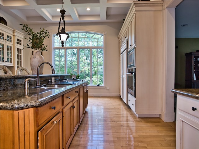 kitchen featuring coffered ceiling, sink, light hardwood / wood-style flooring, beamed ceiling, and stainless steel appliances