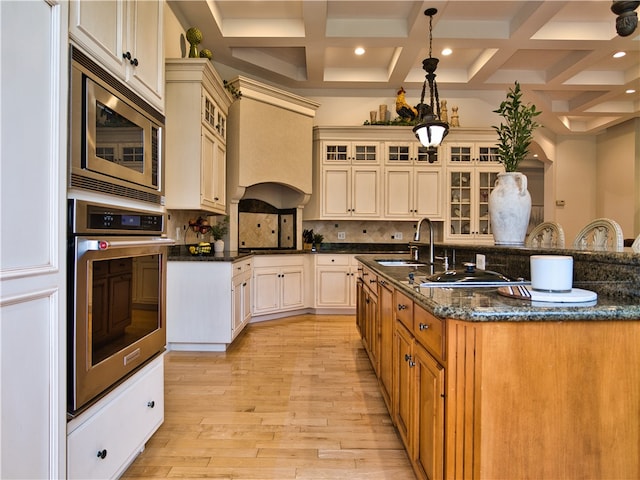 kitchen featuring coffered ceiling, sink, light hardwood / wood-style flooring, beam ceiling, and stainless steel appliances