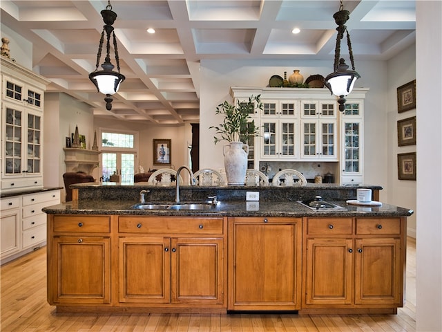 kitchen featuring pendant lighting, light wood-type flooring, sink, and dark stone counters