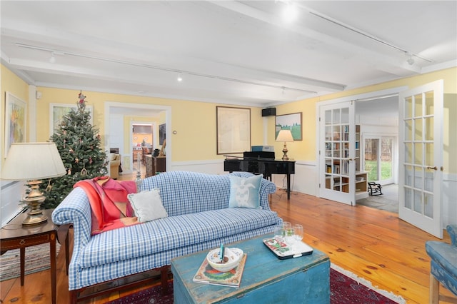 living room with beamed ceiling, french doors, rail lighting, and hardwood / wood-style floors