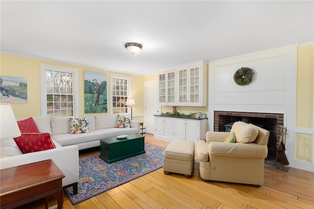 living room featuring a fireplace, crown molding, and light hardwood / wood-style flooring