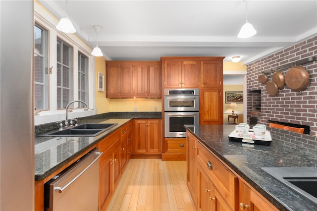 kitchen with sink, pendant lighting, light wood-type flooring, and appliances with stainless steel finishes