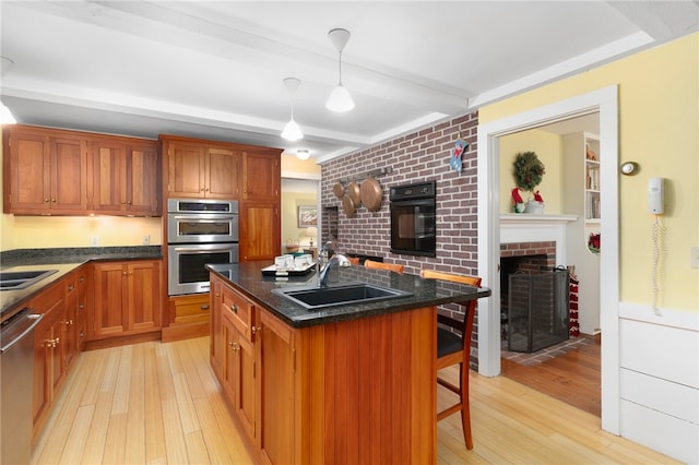 kitchen featuring sink, light hardwood / wood-style floors, a fireplace, a kitchen island, and a breakfast bar area