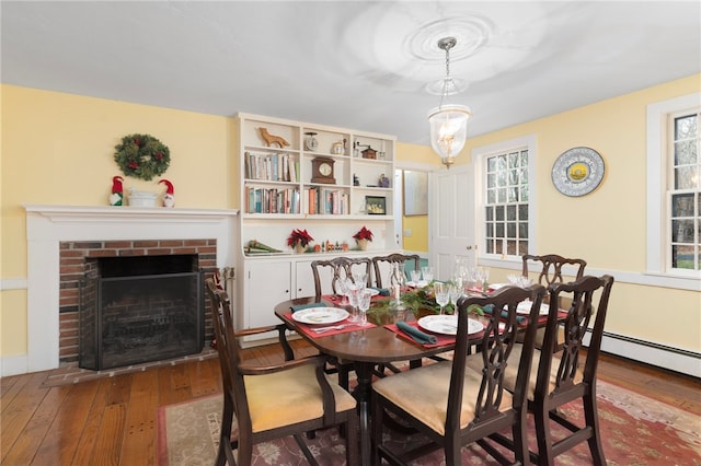 dining space with a brick fireplace and hardwood / wood-style flooring