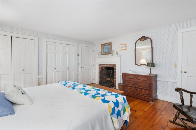 bedroom featuring a fireplace, dark wood-type flooring, and two closets