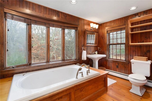 bathroom with hardwood / wood-style flooring, a healthy amount of sunlight, baseboard heating, and wooden walls