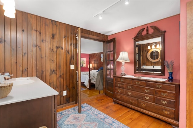 interior space with hardwood / wood-style flooring, vanity, wooden walls, and track lighting