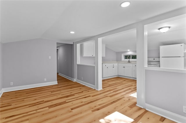 interior space with lofted ceiling, sink, and light hardwood / wood-style flooring