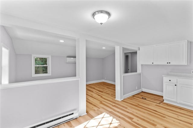 interior space featuring a wall mounted air conditioner, baseboard heating, and light hardwood / wood-style flooring