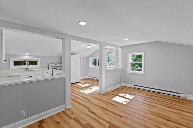 additional living space with light wood-type flooring, vaulted ceiling, baseboard heating, and sink