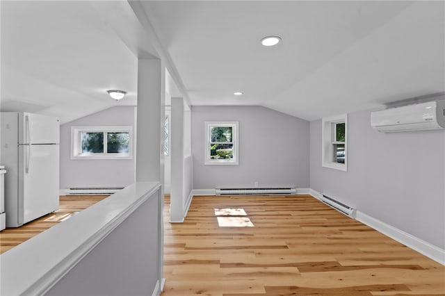 additional living space featuring vaulted ceiling, light wood-type flooring, an AC wall unit, and a baseboard heating unit