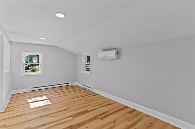 additional living space featuring a wall mounted air conditioner, light hardwood / wood-style floors, vaulted ceiling, and a baseboard heating unit