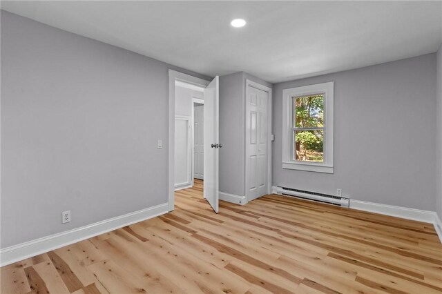 unfurnished bedroom with a closet, light hardwood / wood-style flooring, and a baseboard radiator