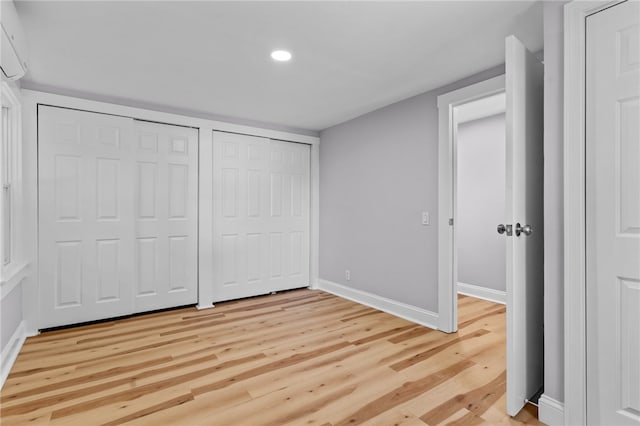 unfurnished bedroom with light hardwood / wood-style floors and multiple closets