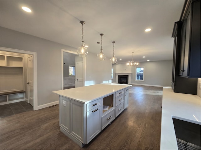 kitchen featuring hanging light fixtures, dark wood-type flooring, a center island, and a healthy amount of sunlight