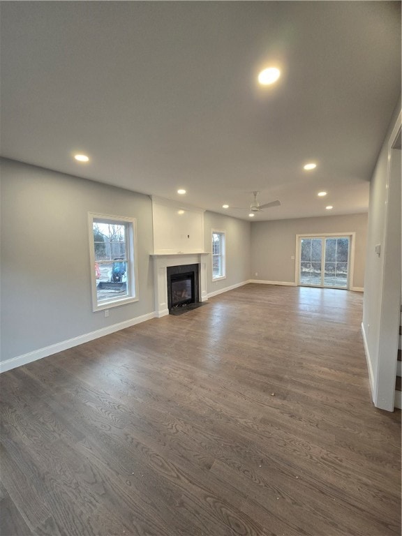 unfurnished living room featuring dark hardwood / wood-style floors and ceiling fan