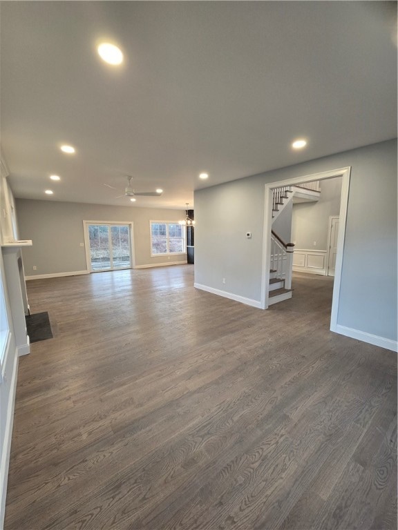 unfurnished living room featuring ceiling fan and dark wood-type flooring