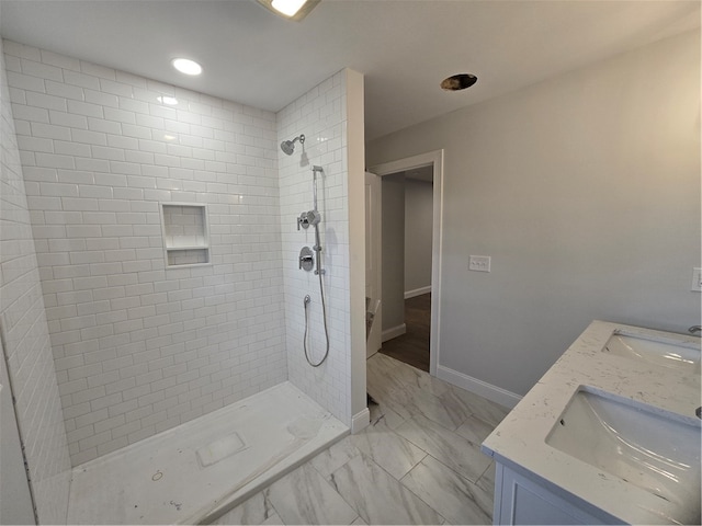 bathroom with a tile shower and vanity