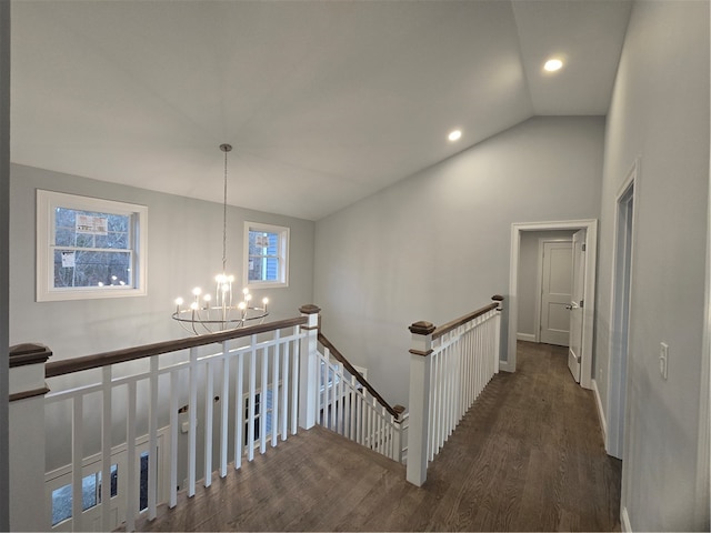 stairs with wood-type flooring, vaulted ceiling, and a notable chandelier