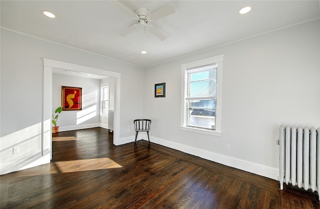 unfurnished room featuring dark hardwood / wood-style floors, ceiling fan, ornamental molding, and radiator