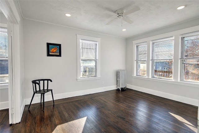 spare room featuring dark hardwood / wood-style floors, plenty of natural light, radiator, and ceiling fan