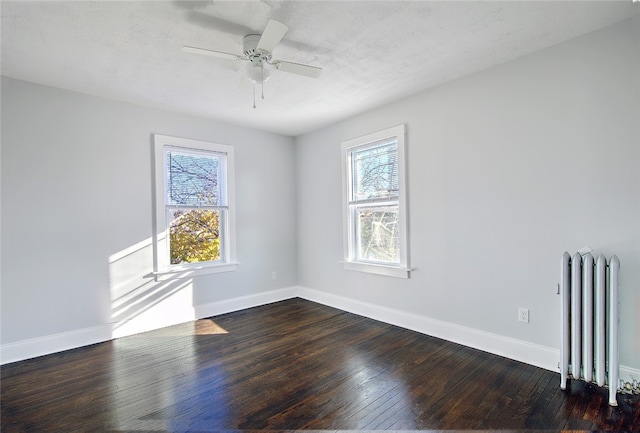 spare room featuring radiator heating unit, a textured ceiling, ceiling fan, and dark wood-type flooring