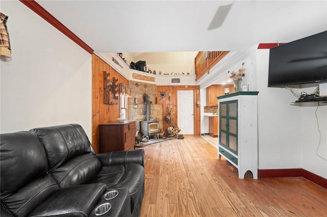 living room with light hardwood / wood-style floors, a wood stove, and ornamental molding