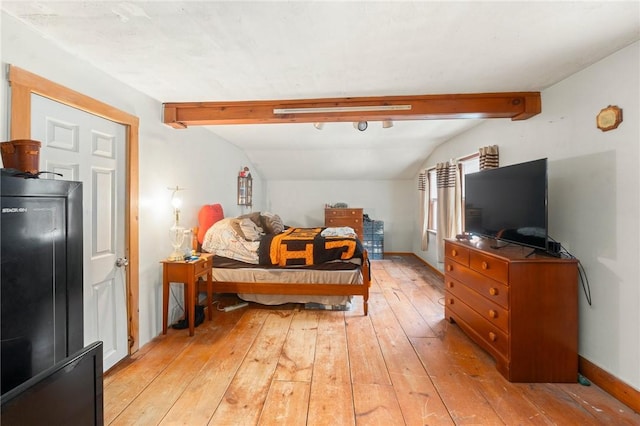 bedroom featuring light wood-type flooring and vaulted ceiling with beams