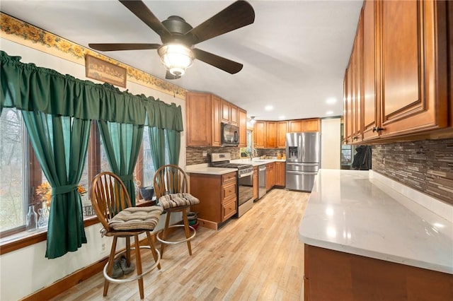 kitchen with backsplash, sink, ceiling fan, light wood-type flooring, and stainless steel appliances