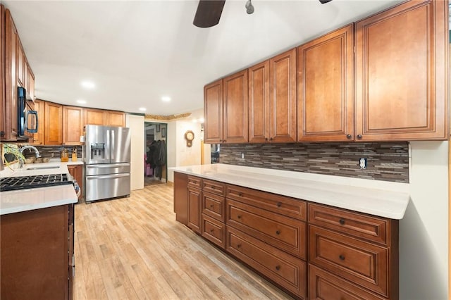 kitchen featuring decorative backsplash, light wood-type flooring, ceiling fan, sink, and stainless steel fridge with ice dispenser