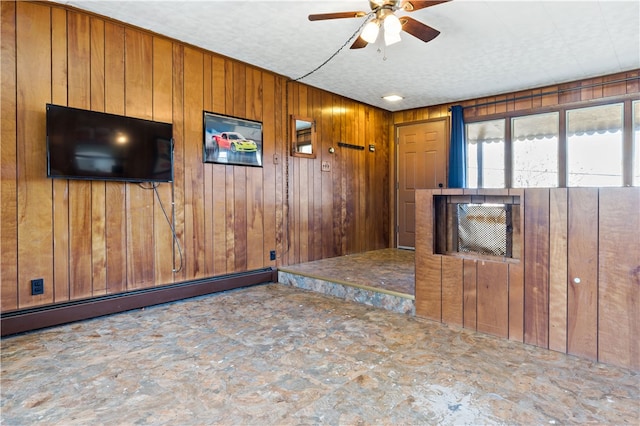 unfurnished living room featuring a baseboard heating unit, ceiling fan, and wooden walls