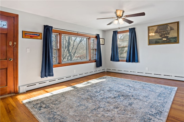 empty room with hardwood / wood-style floors, ceiling fan, and baseboard heating