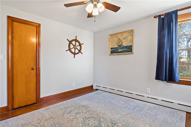 unfurnished room featuring hardwood / wood-style floors, ceiling fan, a wealth of natural light, and a baseboard heating unit