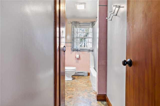 bathroom featuring washtub / shower combination, a baseboard radiator, toilet, and tile walls