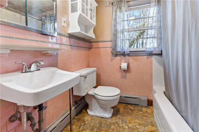 full bathroom featuring shower / tub combo with curtain, baseboard heating, sink, tile walls, and toilet