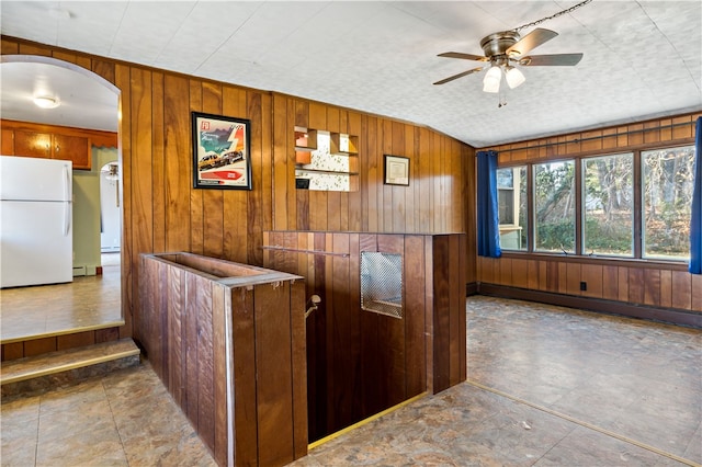 kitchen with wooden walls, white fridge, a baseboard heating unit, and ceiling fan